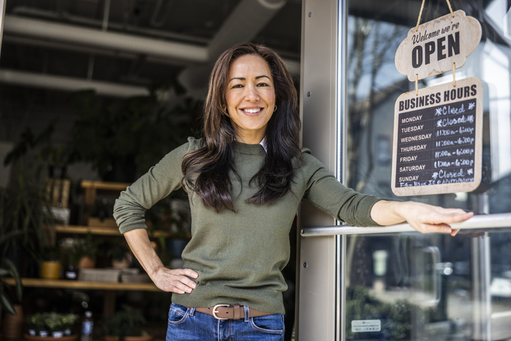 Proud female flower shop owner in front of open sign